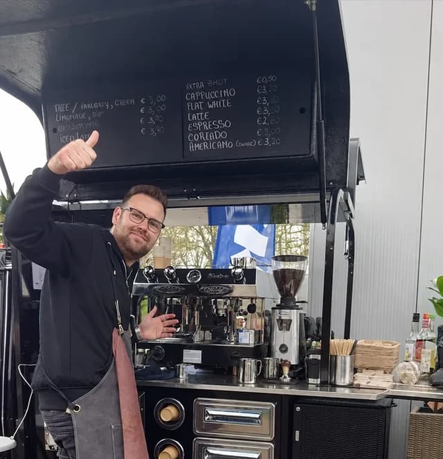 Barista werkt live achter een mobiele koffiekar op een evenement